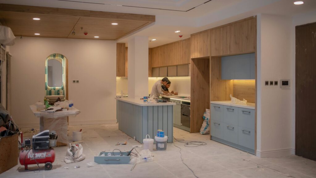 Modern kitchen undergoing renovation with worker, tools, and materials
