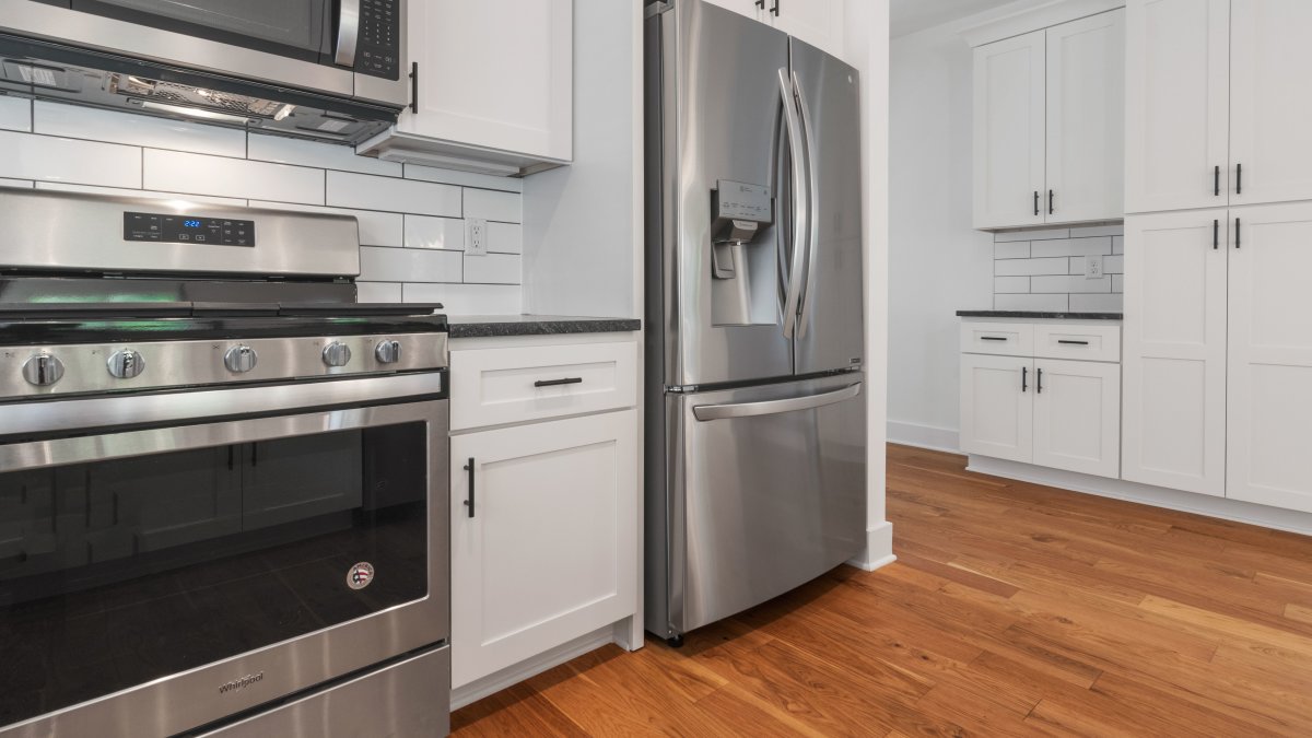 Modern kitchen featuring stainless steel appliances and traditional white cabinetry