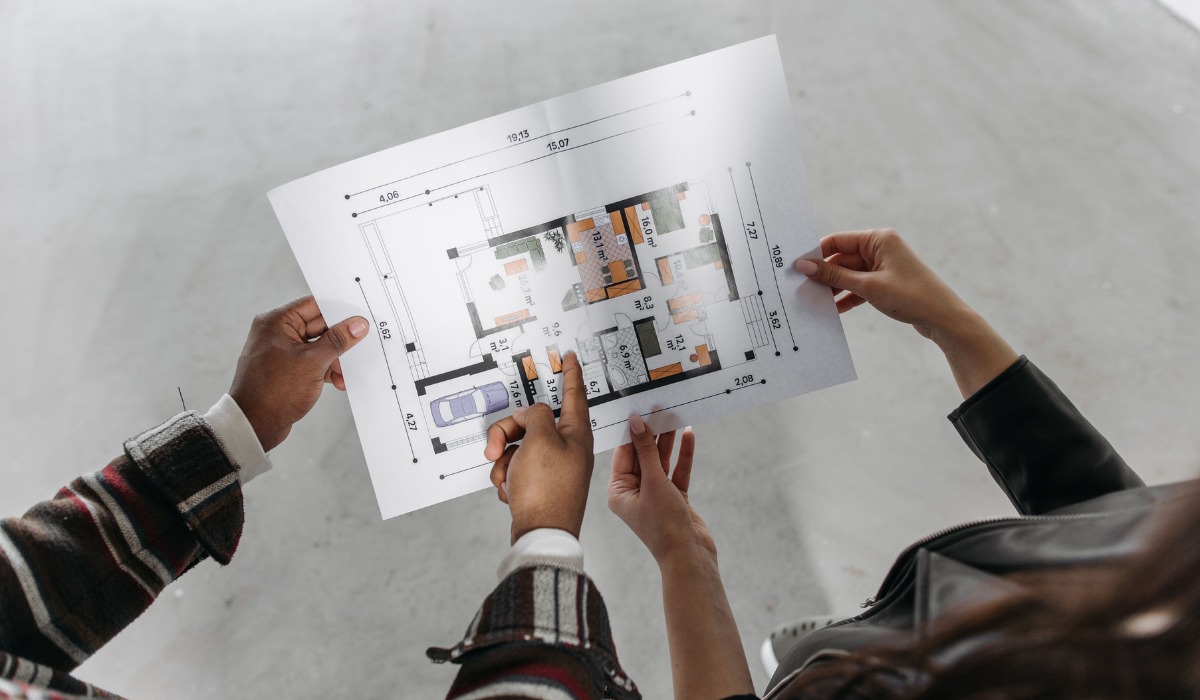 pointing at a printed architectural floor plan