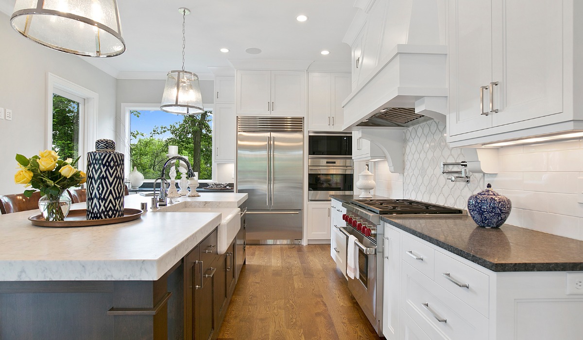Bright white kitchen featuring a large island with a marble countertop